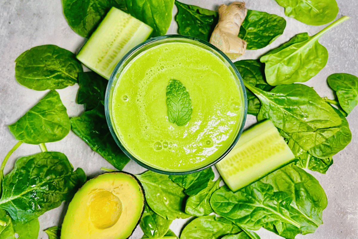 green smoothie surrounded by spinach avocado and cucumber