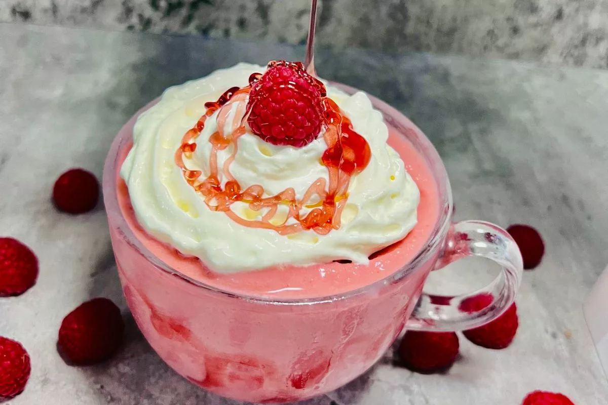 strawberry sauce being drizzled on top of a whipped cream dessert smoothie-min
