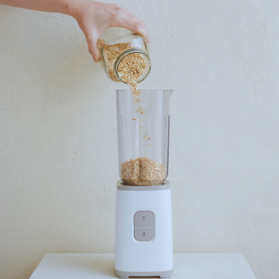 man adding oats to a blender