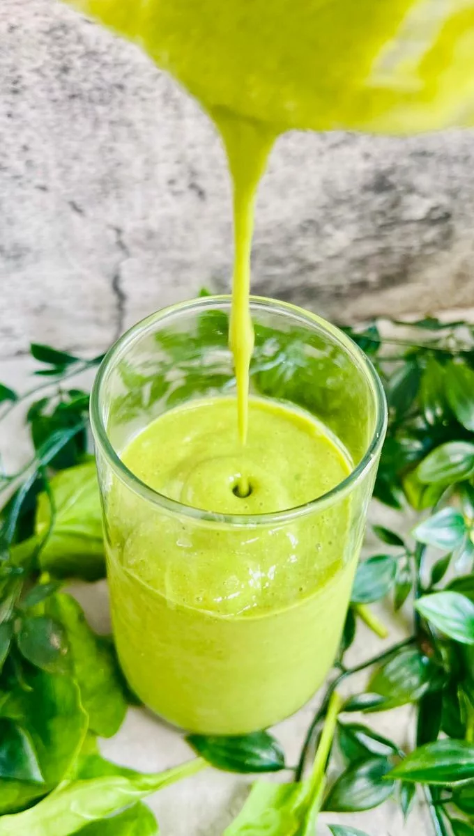Matcha Smoothie For Weight Loss being poured into a thin glass cup from a blender jug