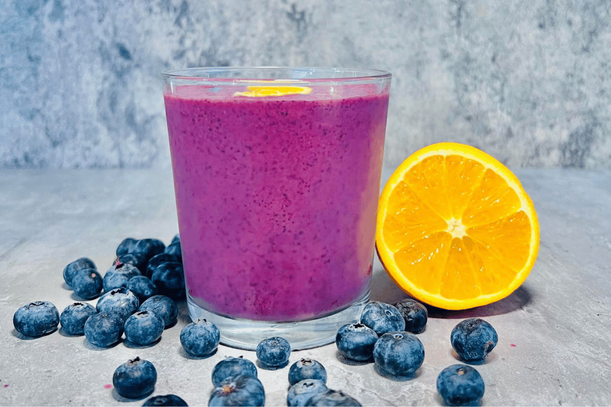 glass-cup-filled-with-a-berry-smoothie-surrounded-by-fresh-blueberries-and-sliced-orange