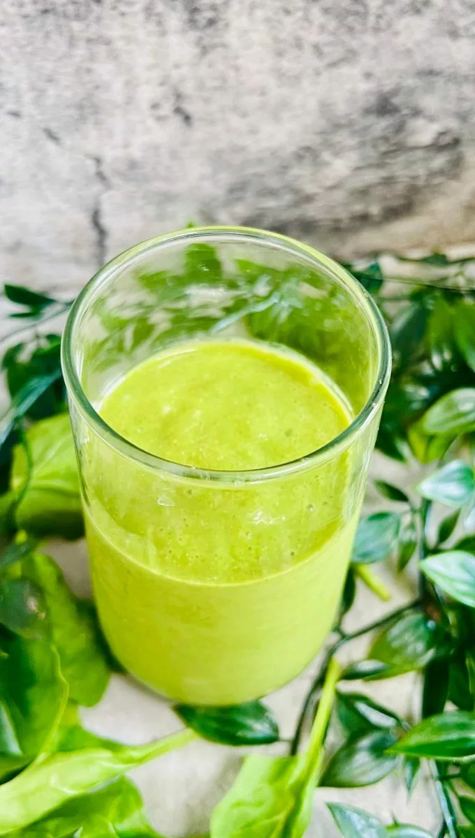 green smoothie surrounded by spinach and other greens