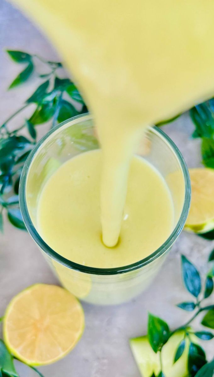 Detox Drink To Lose Belly Fat being poured into a tall thin glass cup from a blender jug
