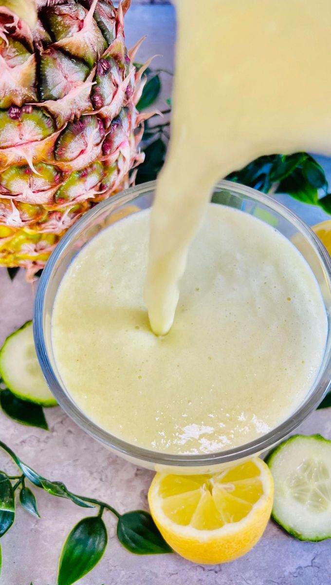 Pineapple Detox Drink being poured into a round glass cup from a blender jug