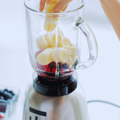 woman adding fruit to a blender