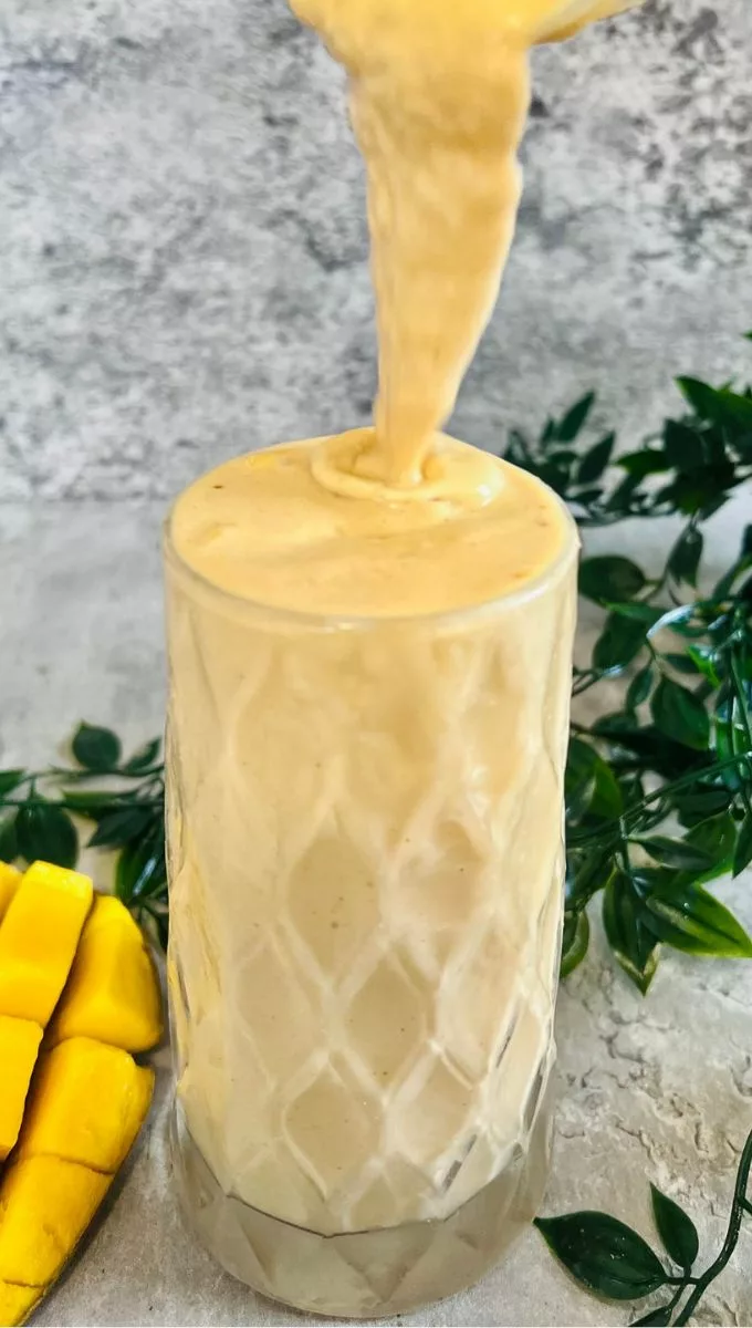 Mango Peanut Butter Smoothie being poured into a thick tall glass cup