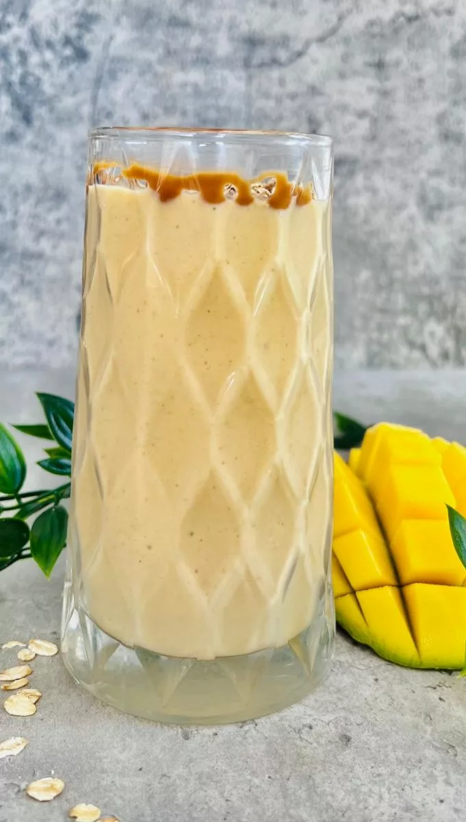 Breakfast Oat Mango Smoothie Served in a tall thick glass cup