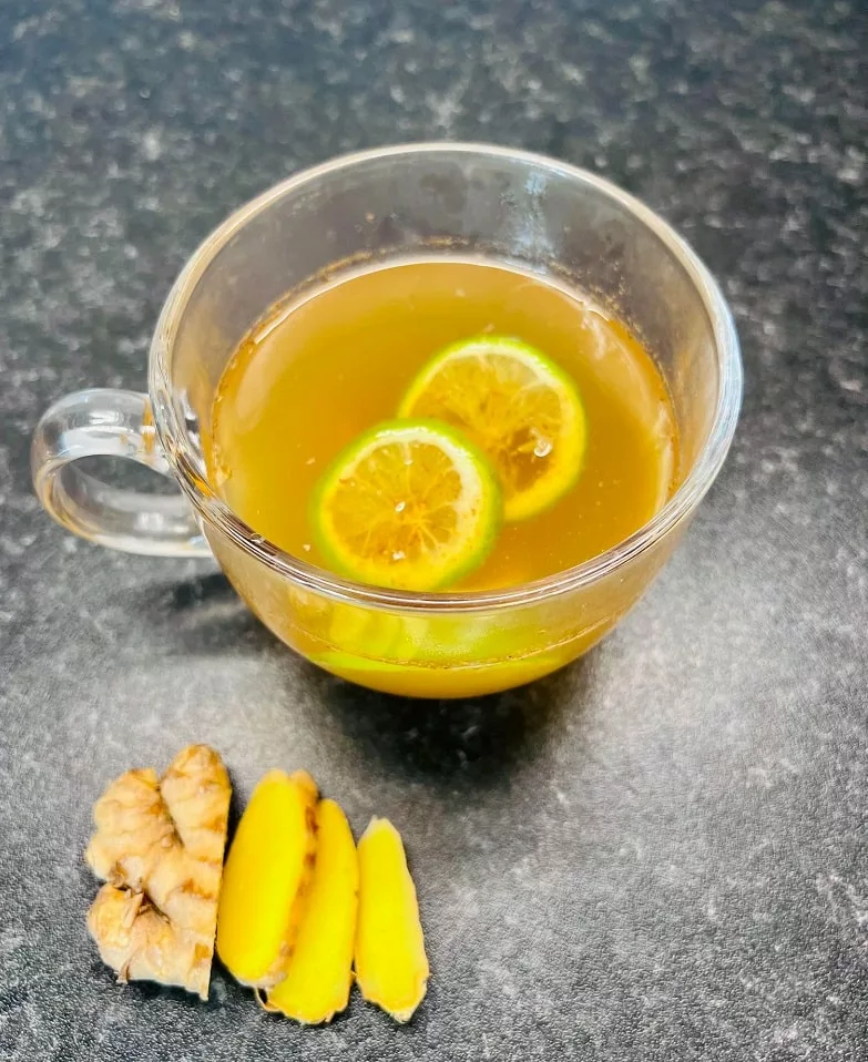 Green Tea Detox Drink with sliced ginger next to it