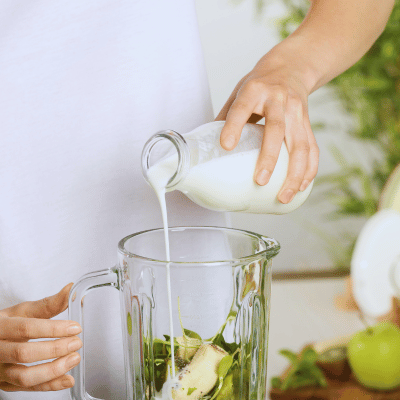 woman adding liquid to a blender to thin smoothie