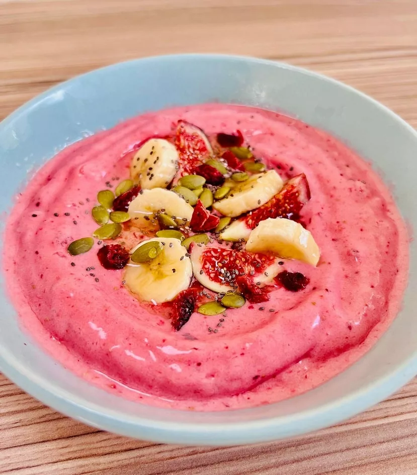 pink smoothie bowl, topped with bananas, chia seeds, figs and pumpkin seeds
