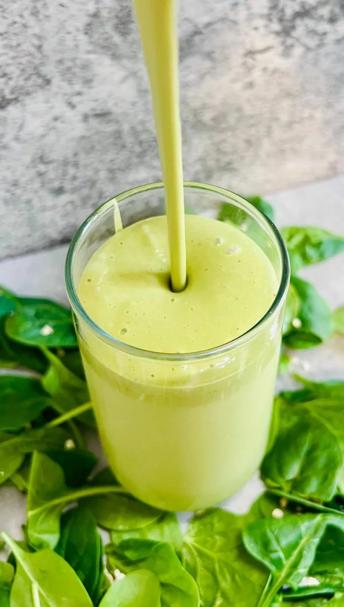 Spinach Peanut Butter Smoothie being poured into a tall glass cup