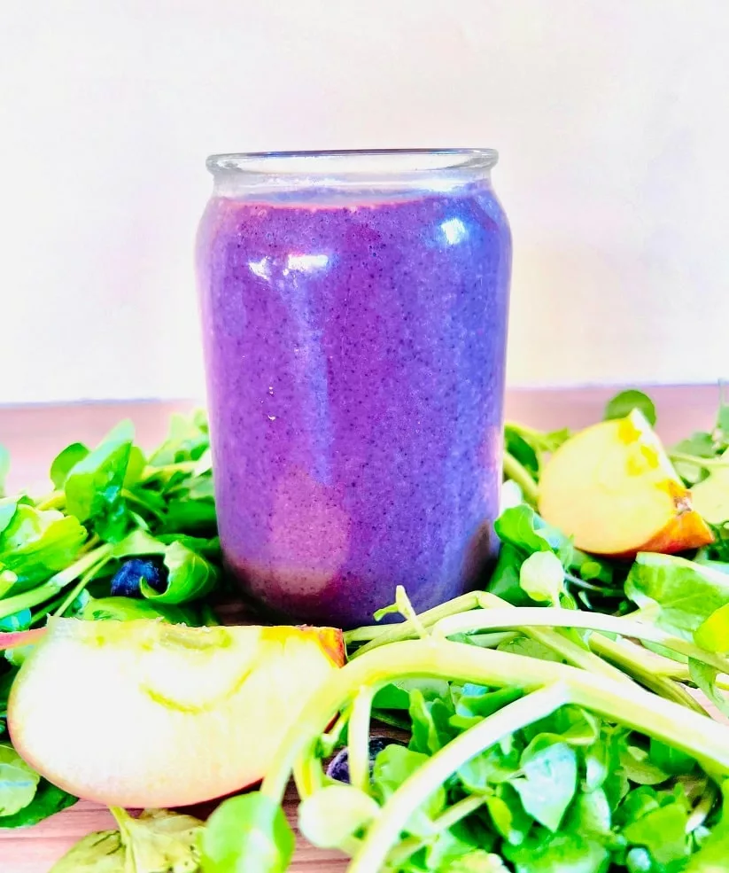 purple colored smoothie with watercress and apple on a wooden surface 