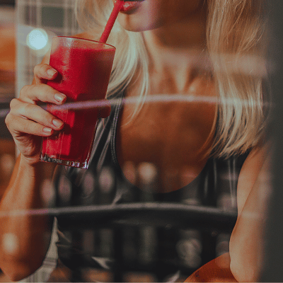 woman drinking a red smoothie using a straw