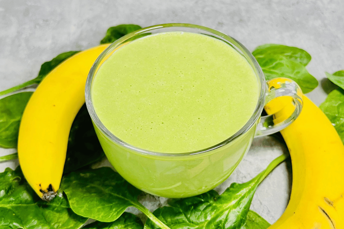 green smoothie made with spinach and banana served in a circle glass cup