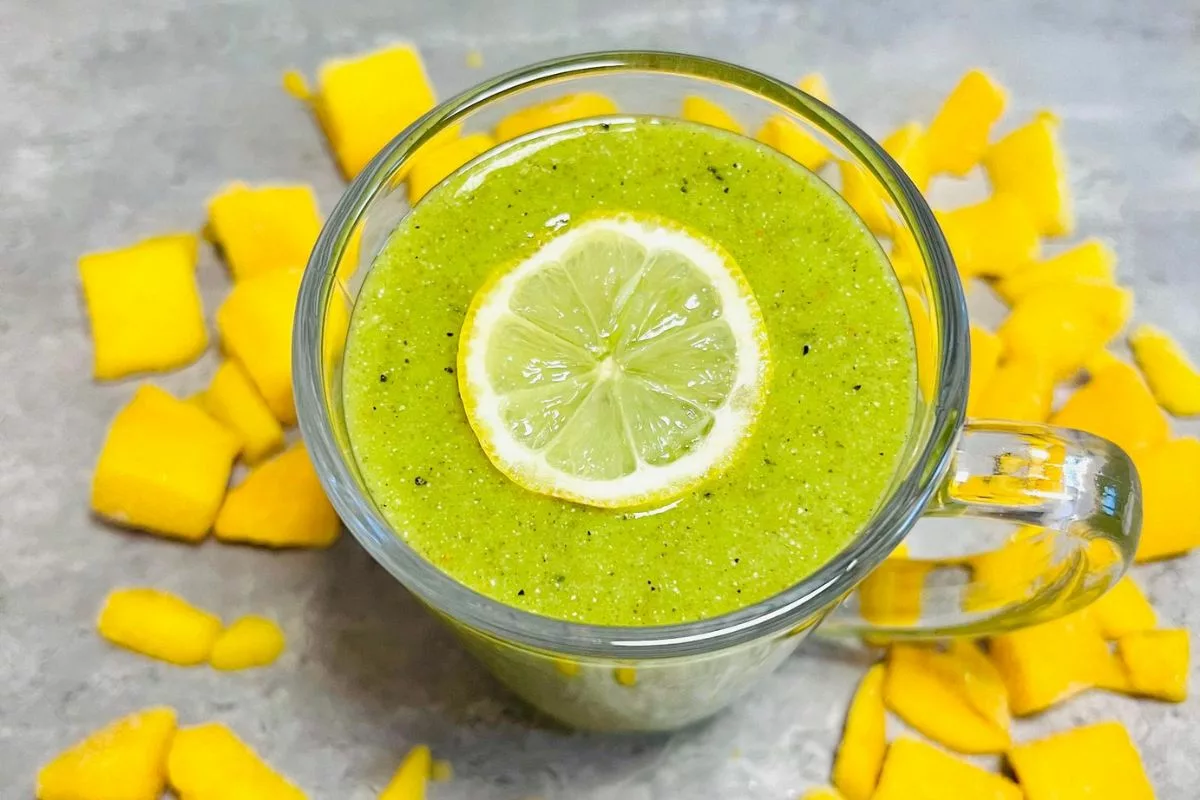 green smoothie topped with a slice of lemon surrounded by mango slices