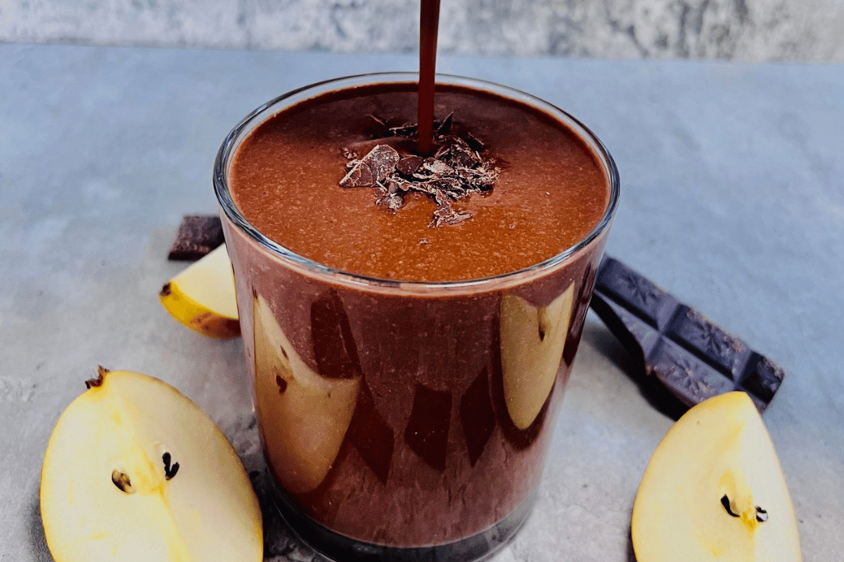 A chocolate smoothie being poured into a glass cup