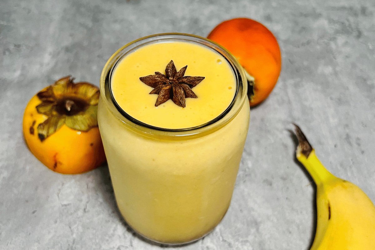persimmon smoothie surrounded by a sliced persimmon and a banana, topped with a star anise