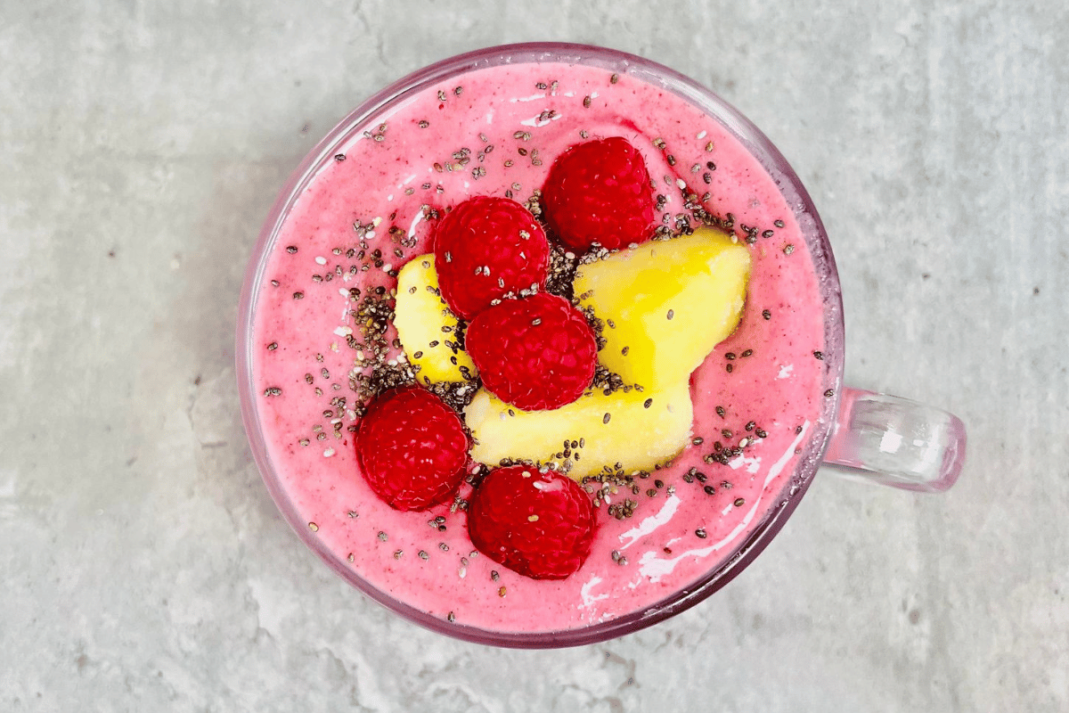 raspberry smoothie topped with pineapple chunks and fresh raspberries