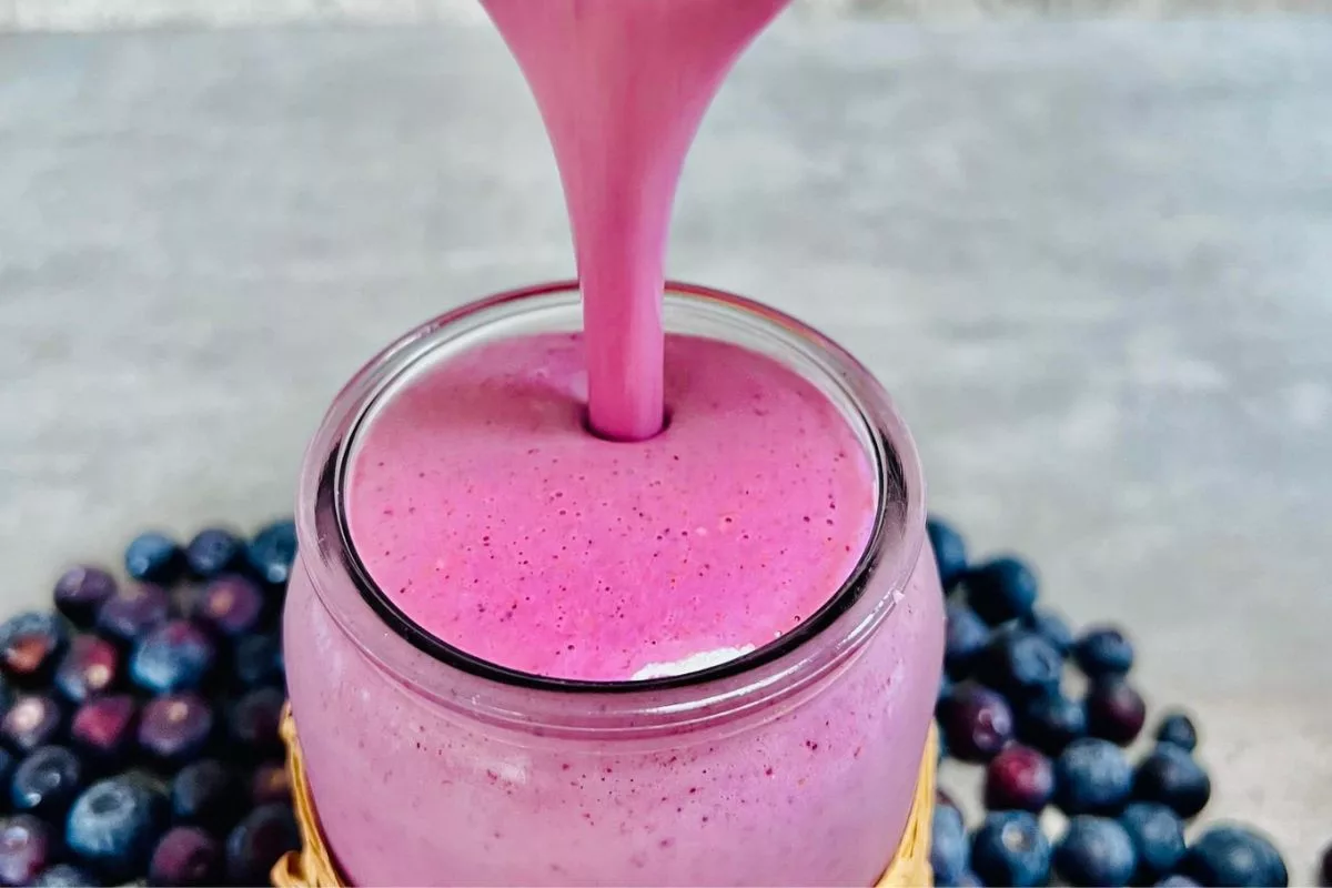 A Fruit Smoothie For Weight Gain being poured into a tall glass cup