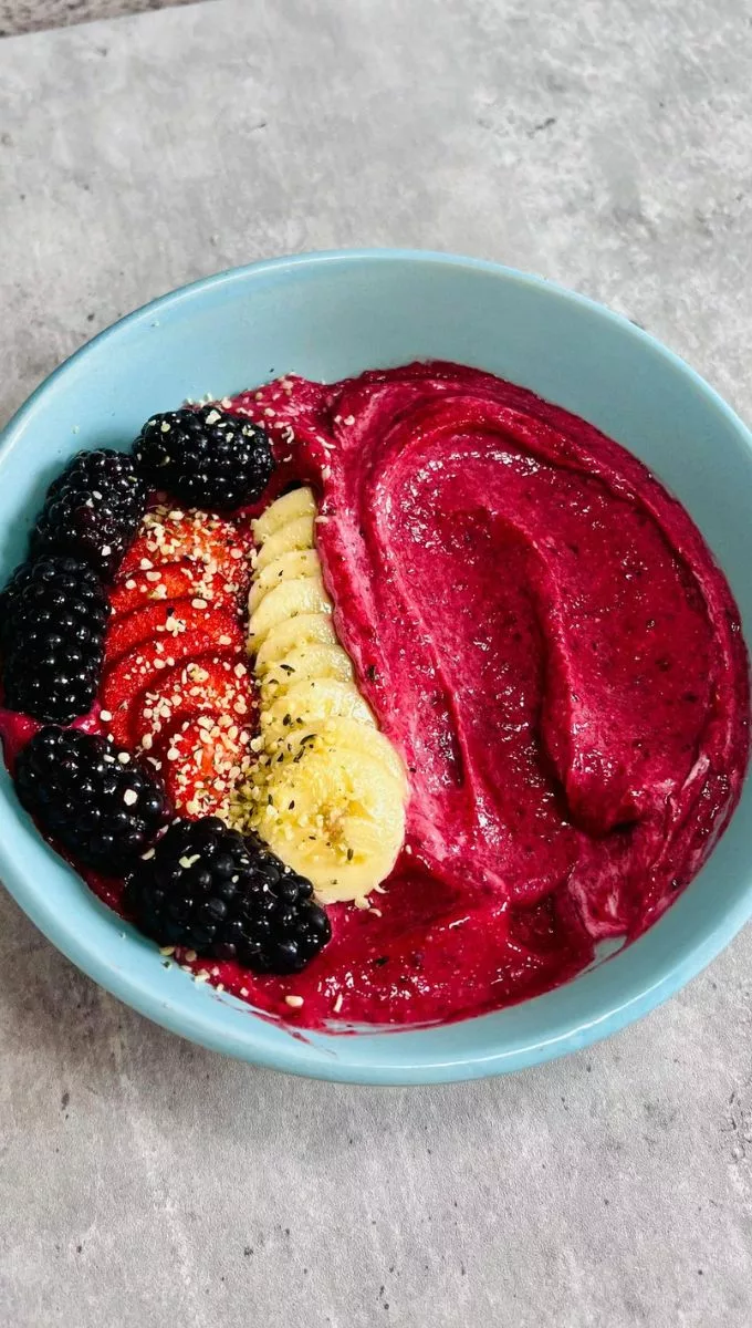 Blackberry Smoothie Bowl served in a blue bowl topped with fresh fruit and seeds