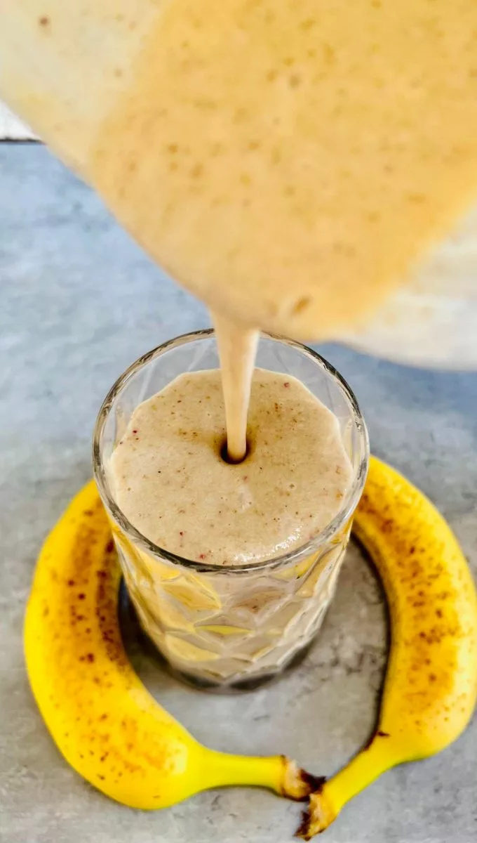 Coconut Milk Banana Smoothie being poured into a tall thick glass cup