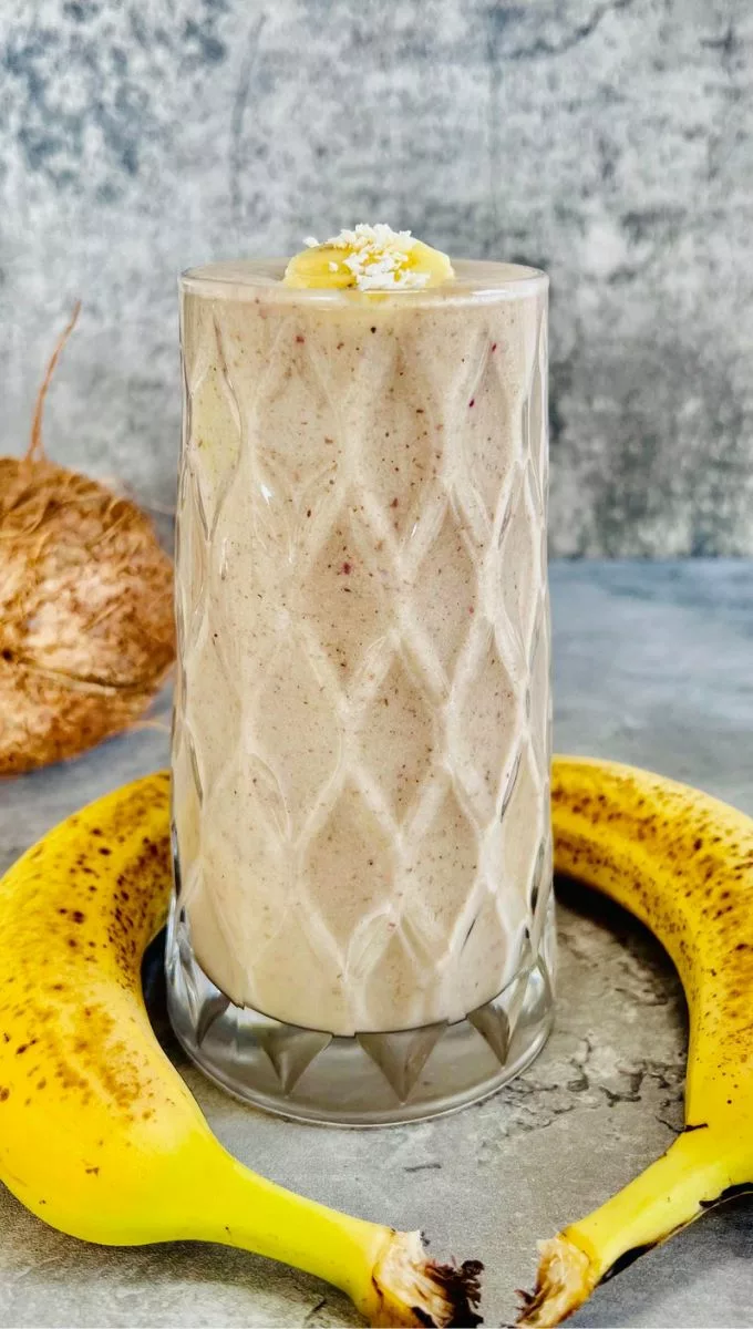 Coconut Milk Banana Smoothie surrounded by fresh banana and a whole coconut