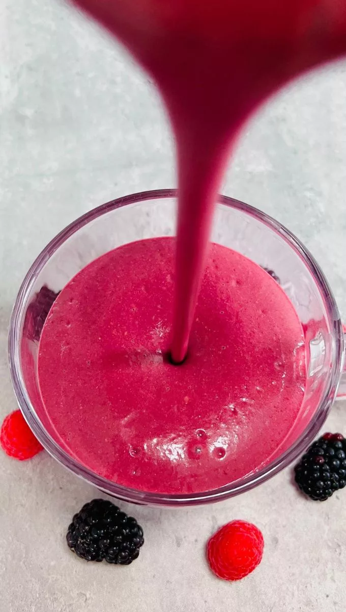 Raspberry Blackberry Smoothie being poured into a round glass cup