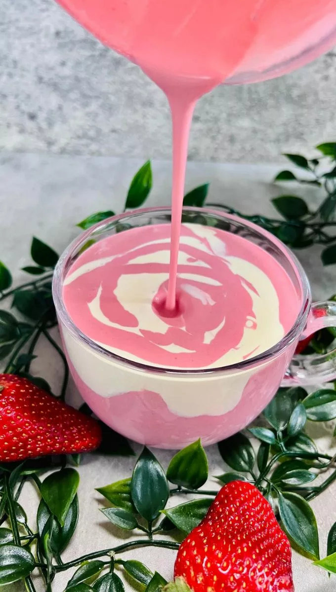 Strawberry And Cream Smoothie being poured into a round glass cup