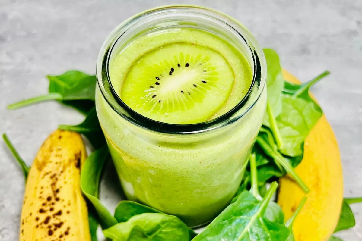 a kiwi smoothie topped with a slice of kiwi surrounded by banana and spinach