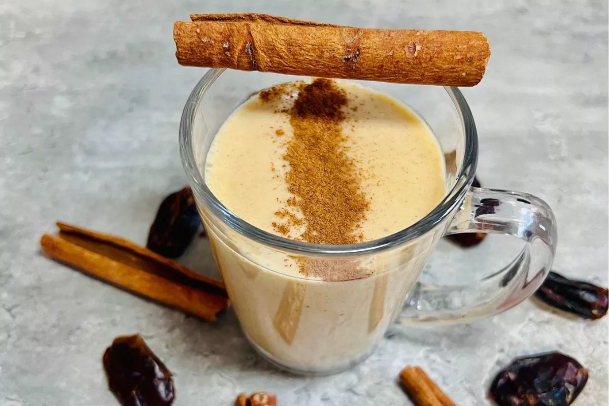 a peanut butter smoothie in a glass cup topped with cinnamon
