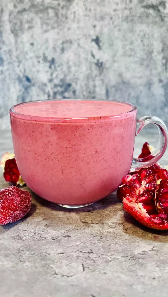 a side shot of a Pomegranate Smoothie with strawberries