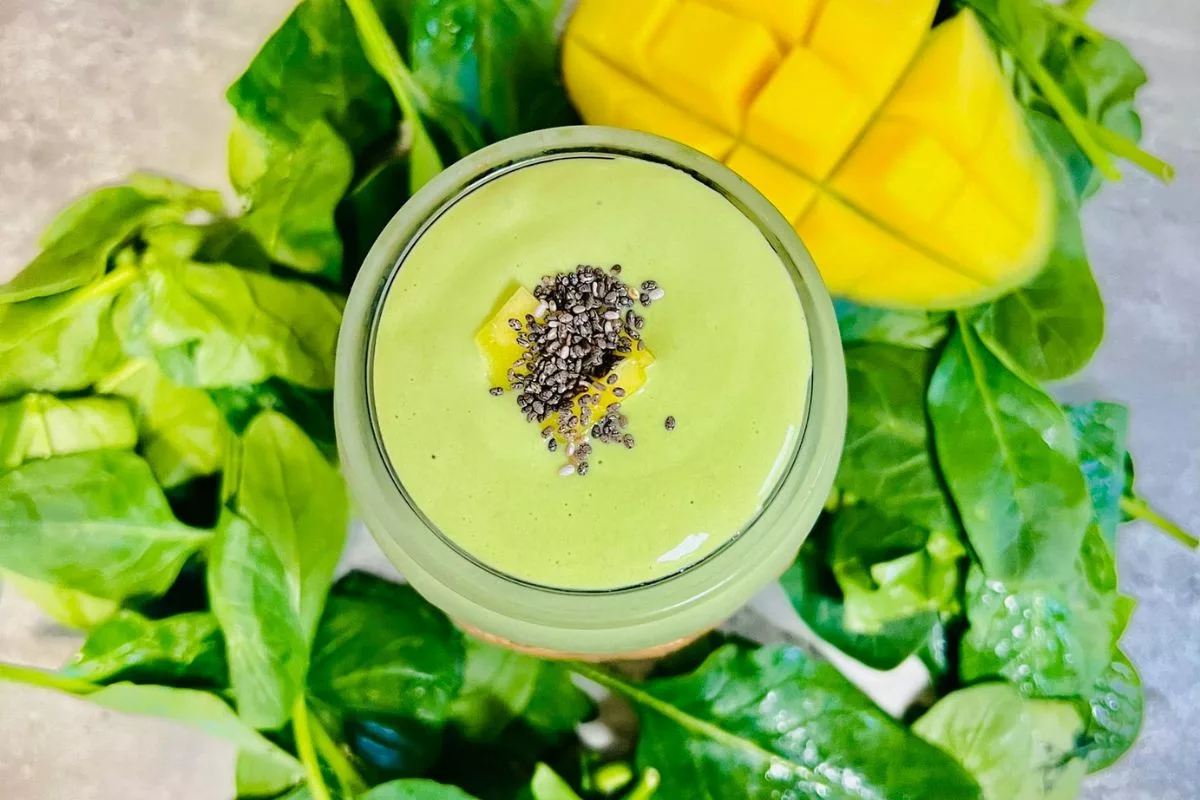 cottage cheese green smoothie surrounded by spinach and fresh mango