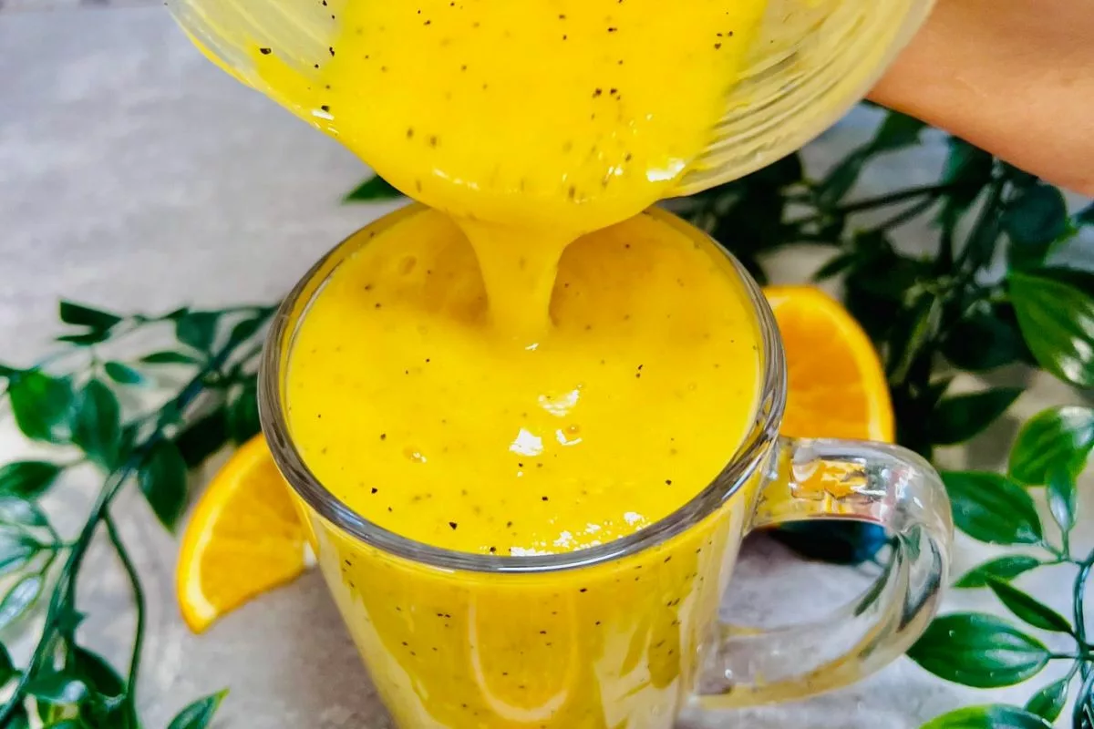 orange passionfruit smoothie being poured into a glass cup