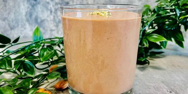 smoothie no protein powder surrounded by fresh almonds and green