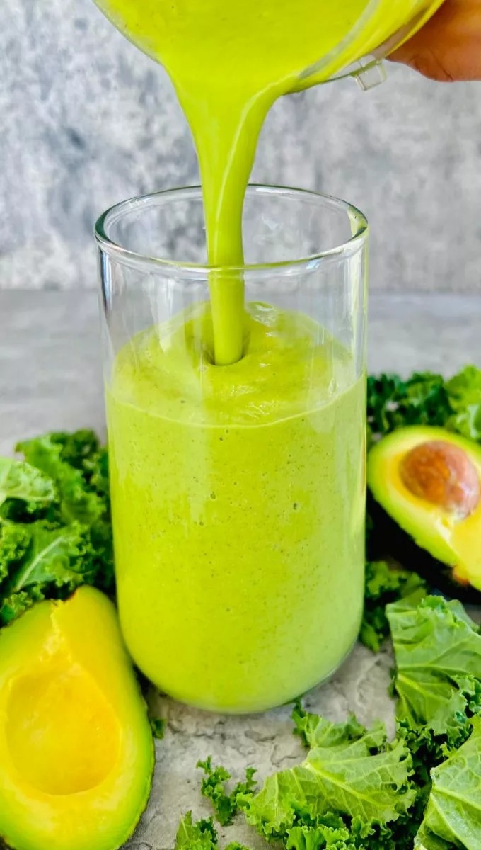 Avocado Smoothie With Coconut Water being poured into a tall glass cup