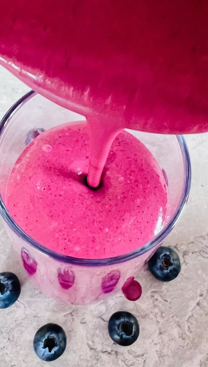 Blueberry Peanut Butter Smoothie being poured into a tall glass cup