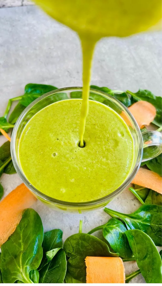 Carrot Spinach Smoothie being poured into a round glass cup