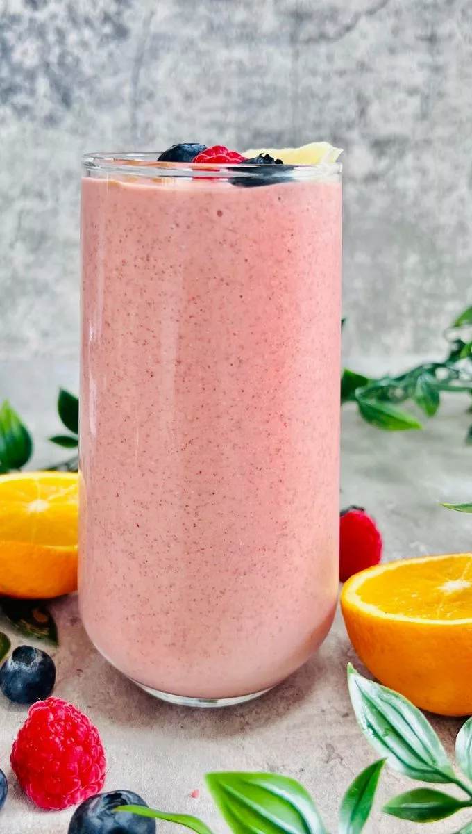 Energy-Boosting Smoothie served in a tall thin glass cup surrounded by fresh berries