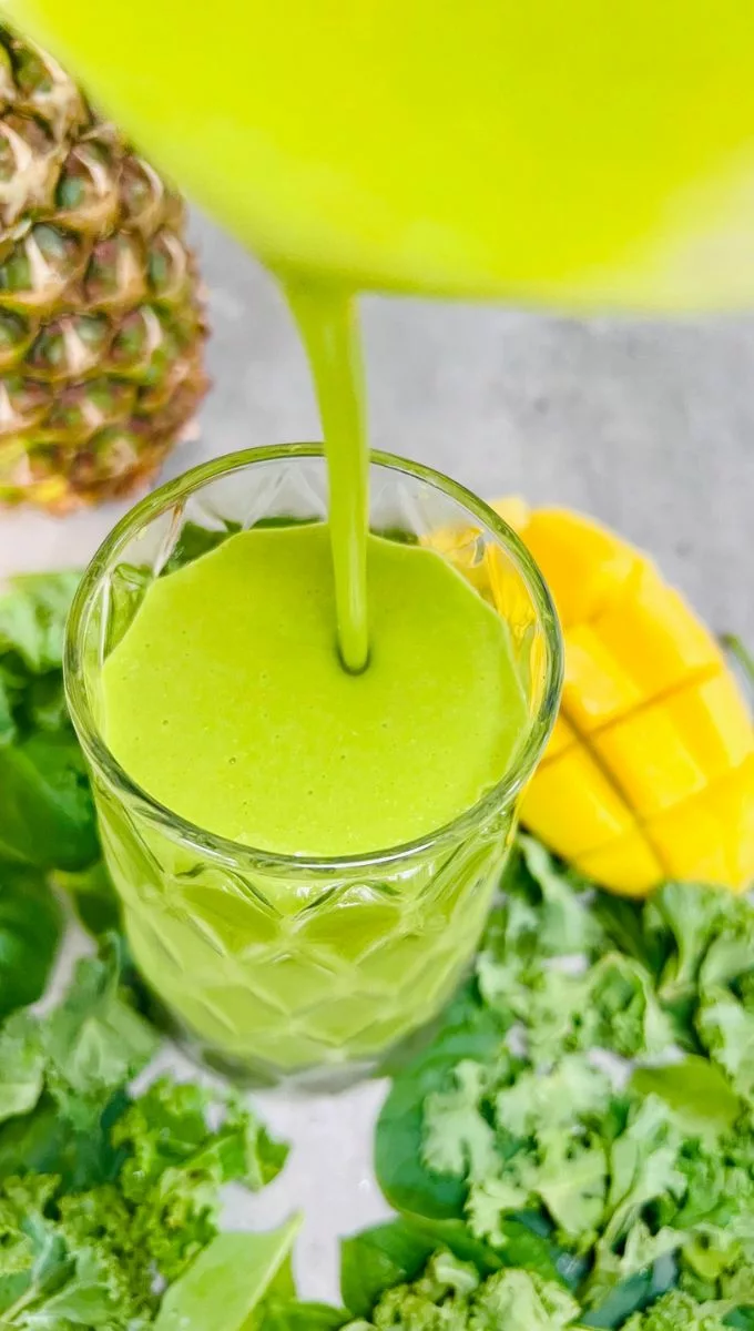 Kale Mango Smoothie being poured into a tall glass cup
