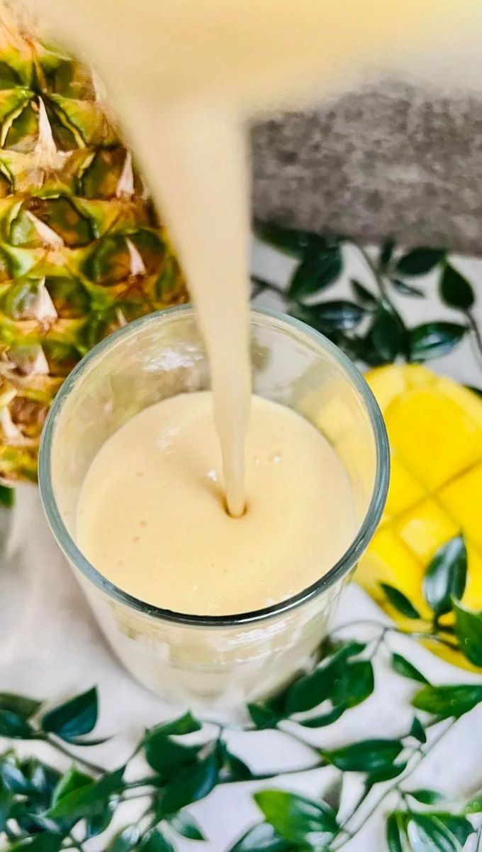Mango And Pineapple Smoothie For Weight Loss being poured into a glass cup