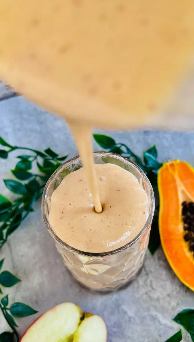 Papaya Smoothie For Weight Loss being poured into a thin glass cup