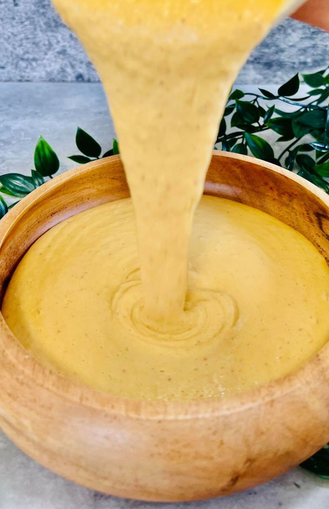 Peach Mango Smoothie Bowl being poured into a wooden bowl