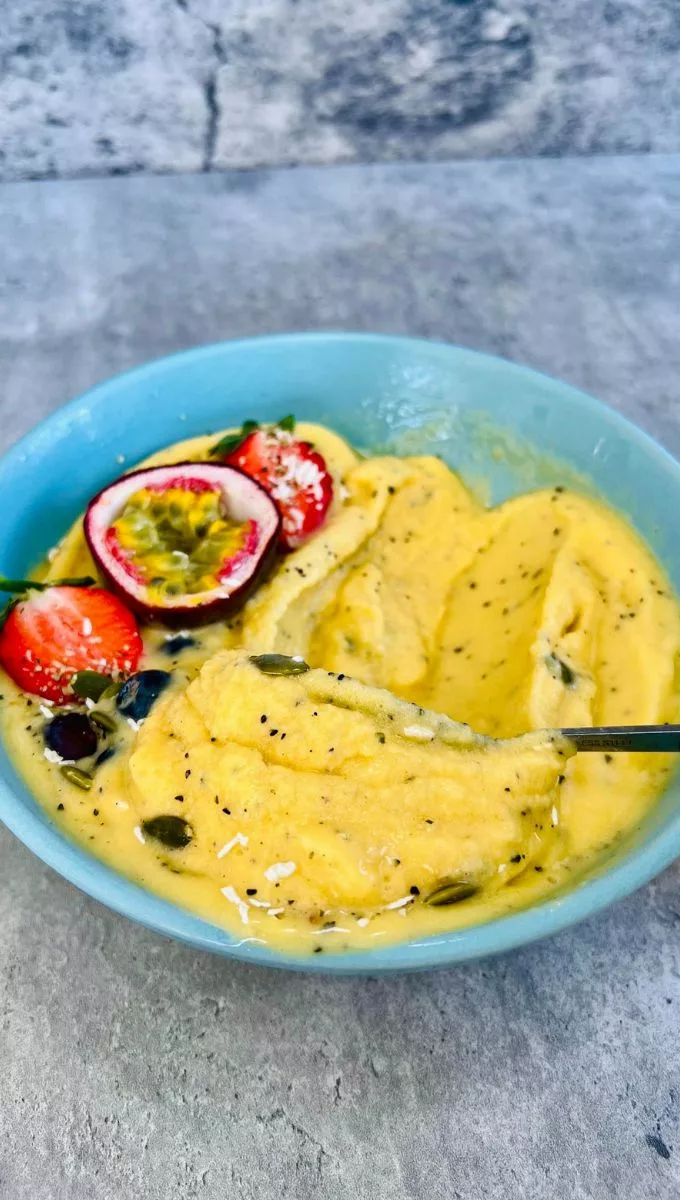 a spoonful of passionfruit smoothie in a blue bowl