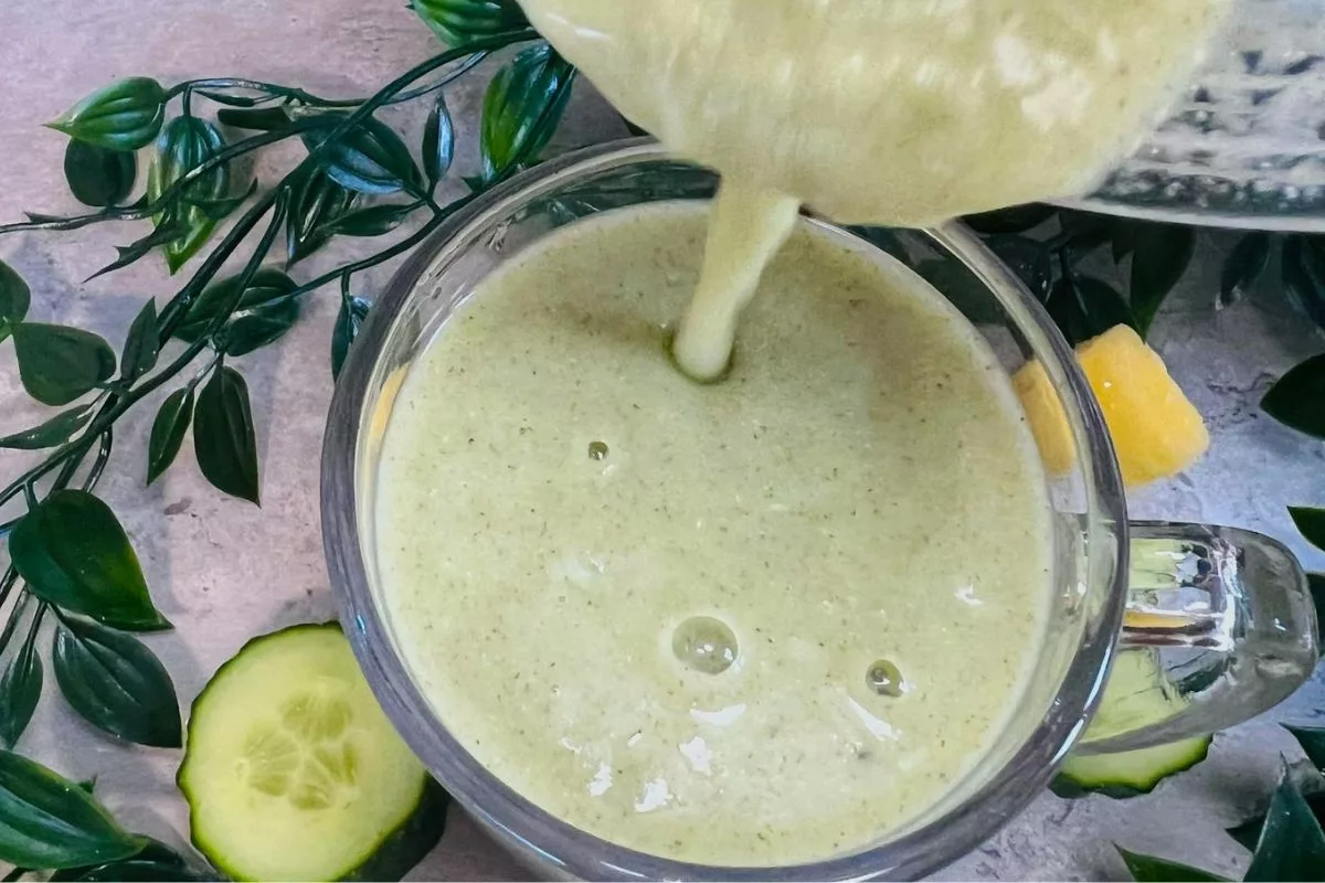 cucumber and pineapple smoothie being poured into a glass cup