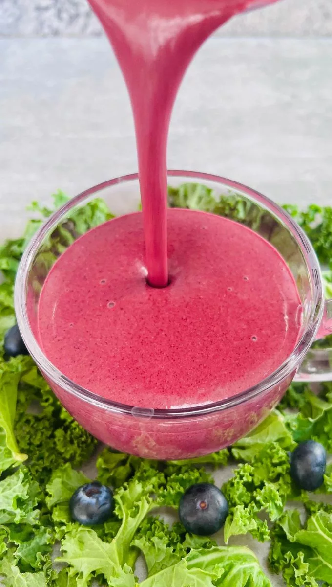 Blueberry Kale Smoothie being poured into a round glass cup