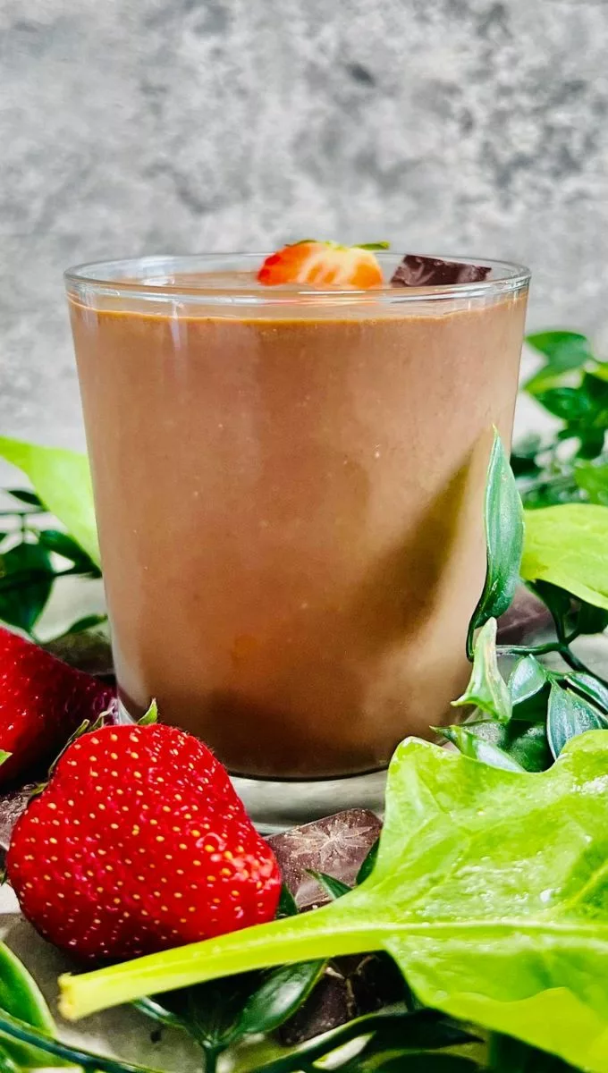Chocolate Protein Smoothie served in a glass cup surrounded by strawberries