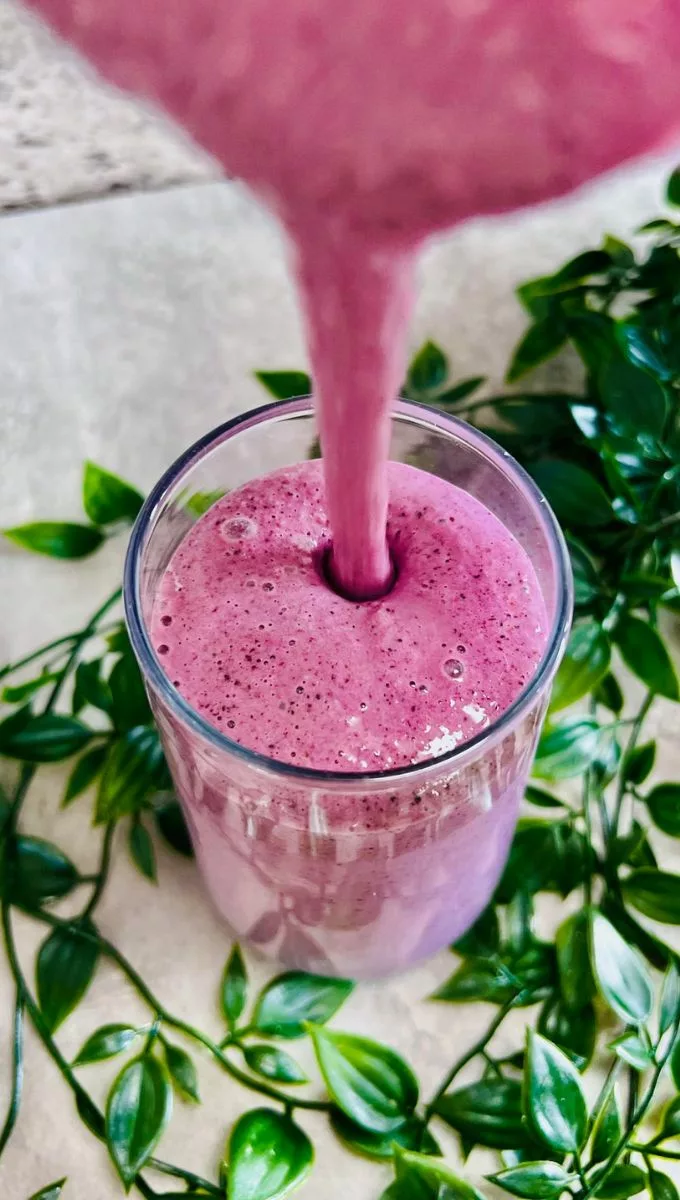 Egg White Smoothie is poured into a glass cup from a blender