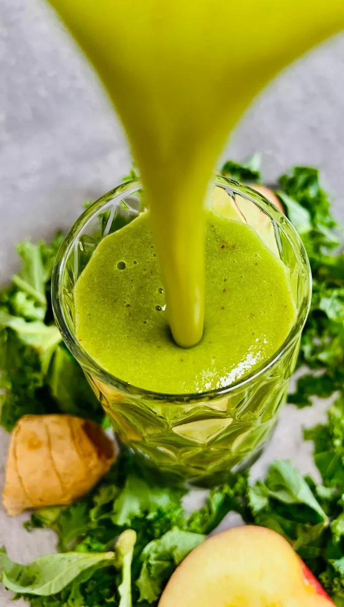 Kale Apple Smoothie being poured into a thick tall glass cup