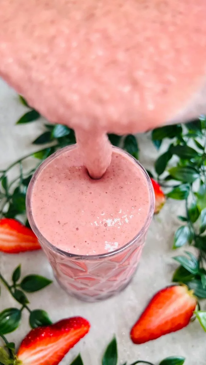 Strawberry Pineapple Banana Smoothie being poured into a glass cup