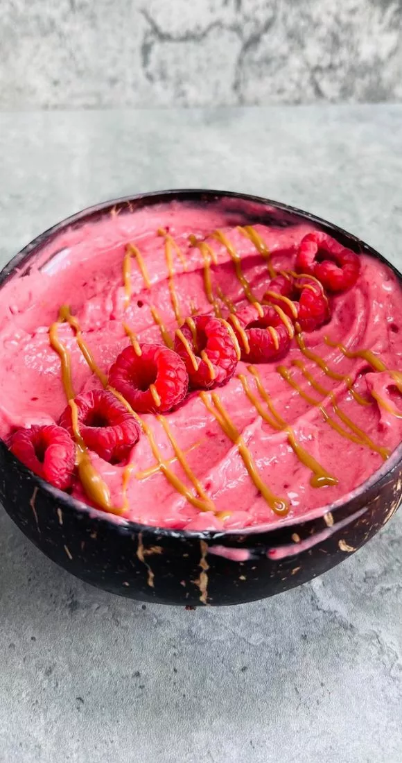raspberry smoothie bowl topped with fresh rasberries